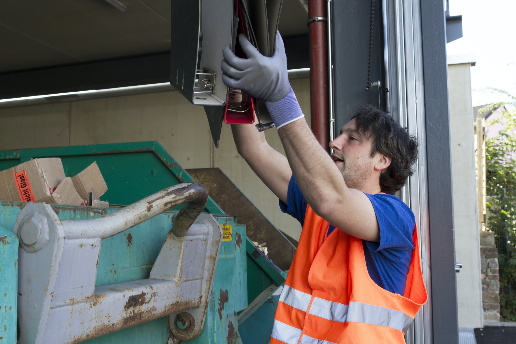 worker-at-a-waste-container-throwing-away-folders.jpg